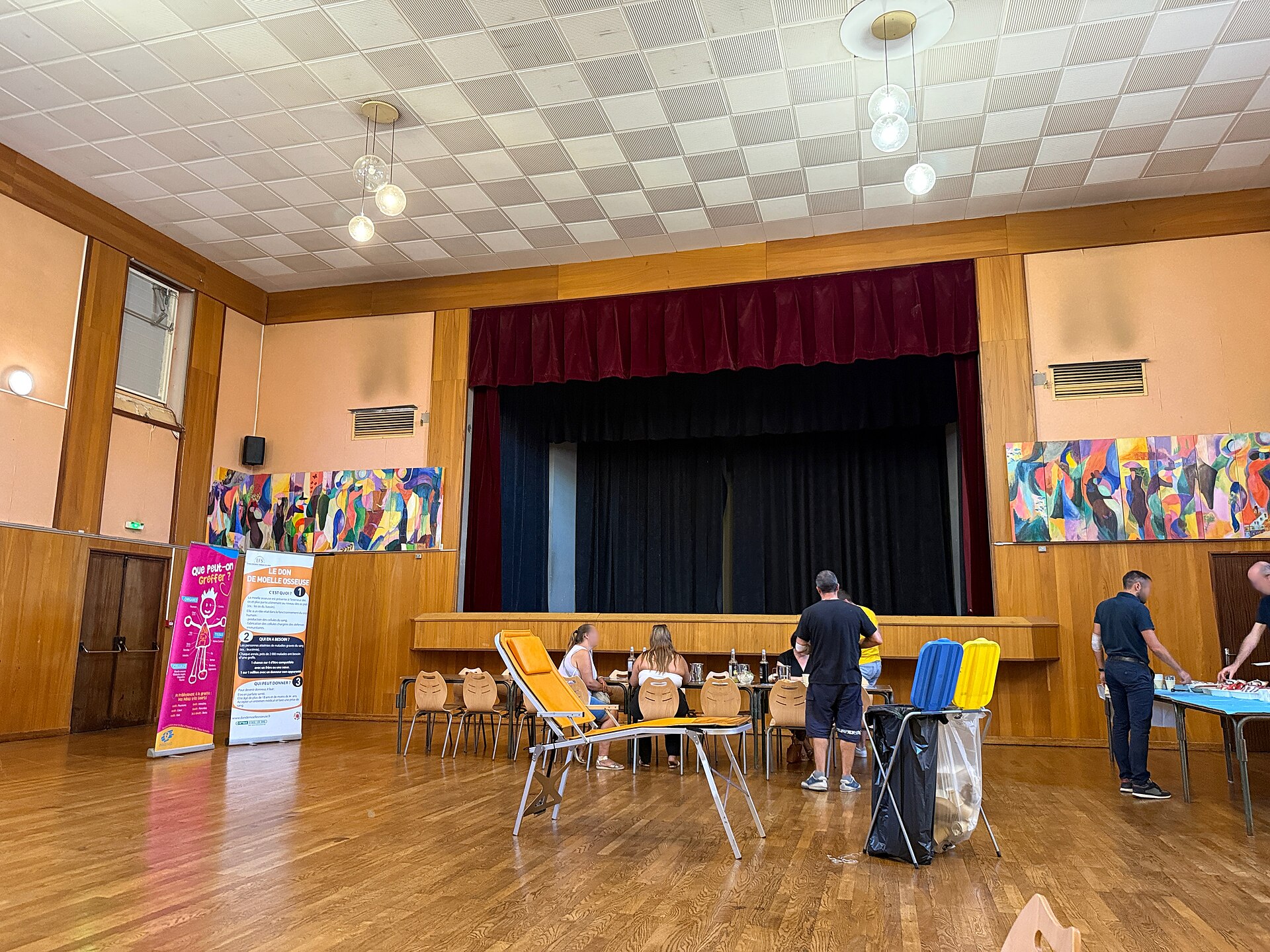 L'intérieur de la salle des fêtes, parquet, scène à rideau rouge et tables installées